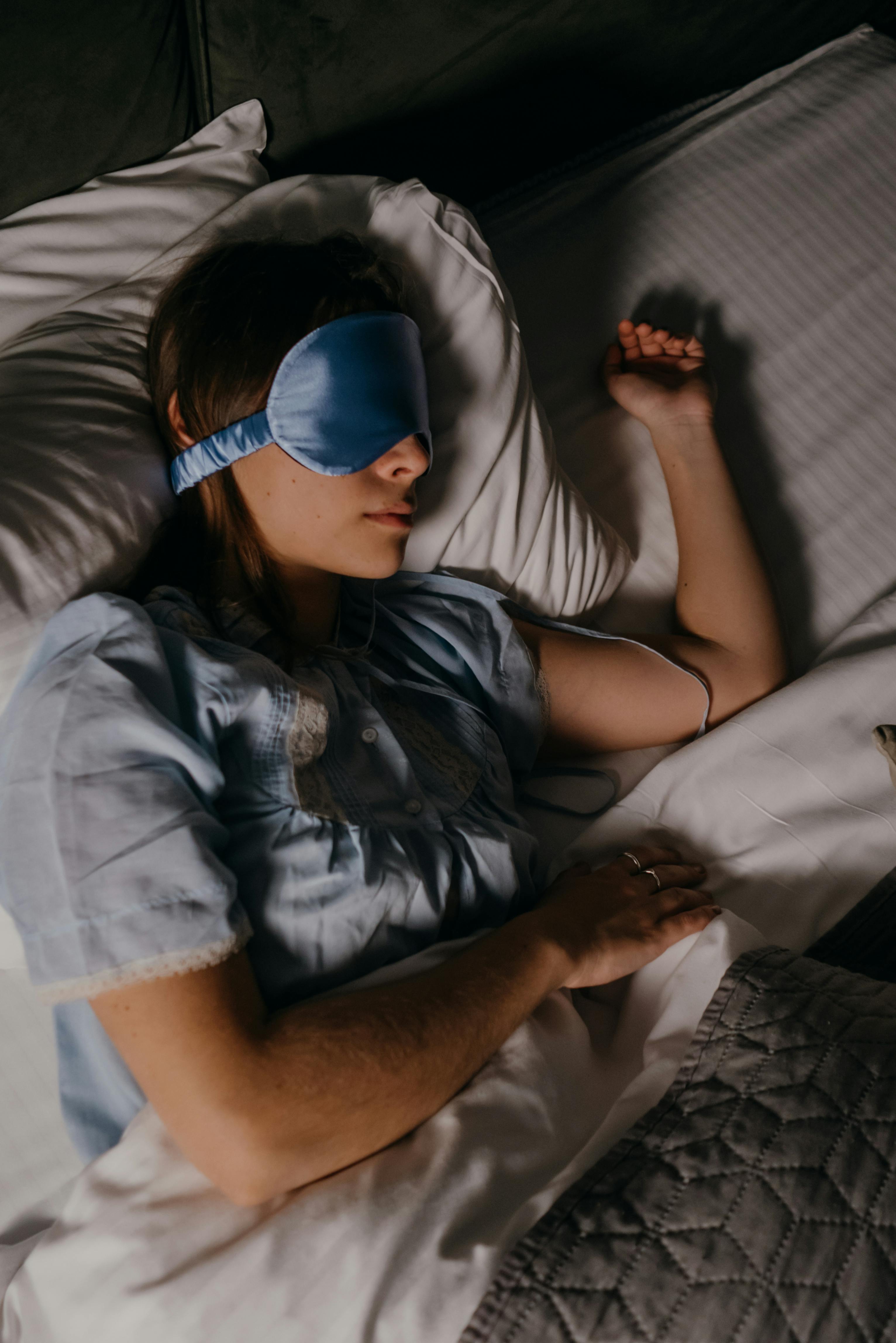 Femme endormie avec masque de sommeil Someira, vue de dessus, draps clairs